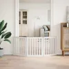 A white wooden pet gate is set up in a doorway, separating two rooms. The gate has three panels, with the middle panel being the widest and the two side panels angled outwards. The gate is made of vertical slats. Voir les images du produit