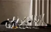 A collection of various glassware, including wine glasses, martini glasses, and a decanter filled with red wine, arranged on a dark wooden table. Produktbild-Vorschau