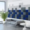 A modern office or waiting room with a sofa, a round table, a plant, and a large window, featuring a wall decorated with acoustic panels. Produktbild-Vorschau