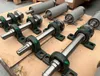 Several industrial components, likely for machinery, are laid out on a wooden surface. Produktbild-Vorschau