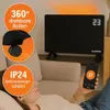 A person is relaxing on a couch while holding a smartphone and looking at a black electric heater in the background. Anteprima dell’immagine prodotto