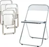 A set of four transparent folding chairs are stacked on the left, and a single transparent folding chair is shown open on the right. Anteprima dell’immagine prodotto