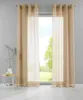 Two sheer curtains hang in front of a window, with a small table and vase to the left.