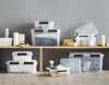 Various plastic storage boxes with lids are displayed on shelves and on the floor. Podgląd zdjęcia produktu