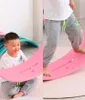 A child is playing with a pink balance board, with another child's legs visible on a similar board in the background. Podgląd zdjęcia produktu