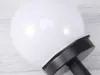 A close-up view of a white spherical solar garden light with a black base, set against a light gray and white wooden surface. Anteprima dell’immagine prodotto