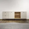 A modern, minimalist lowboard with two drawers on the left, a cabinet with open shelves in the middle, and a cabinet on the right, all set against a plain white wall and a wooden floor. Produktbild-Vorschau