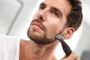 A man is trimming his beard with an electric trimmer. Podgląd zdjęcia produktu