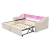 A beige upholstered daybed with a pull-out trundle bed extended, featuring pink LED lighting along the headboard. Produktbild-Vorschau