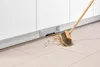 A broom sweeping debris into a built-in vacuum cleaner in a kitchen. Podgląd zdjęcia produktu