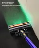 A close-up shot of a purple vacuum cleaner head with a green laser light illuminating dust on a dark floor next to a light-colored wall. Produktbild-Vorschau