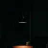 A dark room with a pendant light illuminating a table and a chair. Náhled obrázku produktu