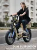 A woman rides an electric bicycle on a paved street in front of a building. Produktbild-Vorschau