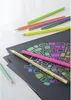 Several colored pencils are arranged on top of black paper with a colorful drawing on it. Anteprima dell’immagine prodotto