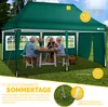 A family is enjoying a meal under a green pop-up gazebo in a grassy backyard. Anteprima dell’immagine prodotto