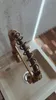 A close-up shot of a kitchen faucet with a coiled hose, set against a sink and a textured wall. Anteprima dell’immagine prodotto