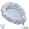 A light blue braided baby nest with a matching pillow, laid out on a white background. Produktbild-Vorschau