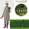 A woman in gardening attire holding a potted plant, with a close-up of a fence and a hedge with size indicators. Náhled obrázku produktu