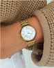 A close-up shot of a woman's wrist wearing a gold Emporio Armani watch, with her arm resting on a beige knitted sweater. Produktbild-Vorschau