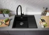 A black granite kitchen sink with a black faucet is shown on a gray countertop, with some kitchen accessories and plants in the background. Produktbild-Vorschau