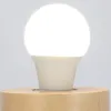 A close-up of an LED light bulb with a motion and twilight sensor, mounted on a wooden base. Podgląd zdjęcia produktu