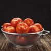 Tomatoes in a colander on a wooden surface. Anteprima dell’immagine prodotto