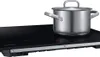 A stainless steel pot on a black induction cooktop. Náhľad obrázku produktu