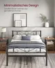A minimalist bedroom scene featuring a black metal bed frame with bedding. Produktbild-Vorschau