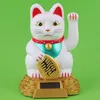 A solar-powered lucky cat figurine on a gold base against a green background. Produktbild-Vorschau