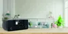 A black DAB+ radio is placed on a wooden table in a living room setting. Produktbild-Vorschau