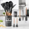 A set of kitchen utensils in a holder, with additional utensils and a container on a countertop in a kitchen setting. Náhľad obrázku produktu