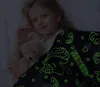A young girl lying in bed with a teddy bear, covered by a glow-in-the-dark unicorn blanket. Náhled obrázku produktu