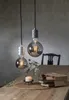 Two decorative LED light bulbs hang above a wooden table, which is set with a candle, a glass bottle, and books. Podgląd zdjęcia produktu
