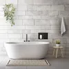 A modern bathroom with a freestanding bathtub, tiled walls, and a hanging plant. Podgląd zdjęcia produktu