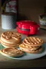 A stack of waffles and a waffle maker on a table. Produktbild-Vorschau