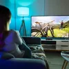 A person is sitting on a couch watching a TV that displays a person with a bicycle in a mountainous landscape. Voir les images du produit
