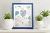 A dark blue picture frame with a botanical print is displayed on a shelf, flanked by potted plants. Náhľad obrázku produktu