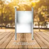 A metal gate-like structure is placed on a wooden surface with a blurred background of trees. Produktbild-Vorschau