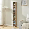A tall, narrow bookshelf filled with CDs and decorative items stands next to a floor lamp and a sofa in a living room. Náhľad obrázku produktu
