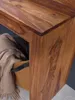 Close-up of a wooden table corner with a basket and blanket underneath. Anteprima dell’immagine prodotto