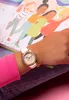 A child's arm wearing a watch is shown next to an open book with illustrations of children. Anteprima dell’immagine prodotto