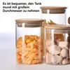 Three glass storage jars with bamboo lids, filled with different food items, are arranged on a white surface. Produktbild-Vorschau