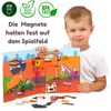A young boy holds open a magnetic construction site playset, showing various vehicles and building elements. Produktbild-Vorschau