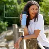 A woman holding a blue travel mug outdoors, leaning on a wooden post. Náhled obrázku produktu