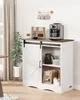 A coffee bar cabinet with a coffee maker and cups displayed on top, and coffee bags and a carafe inside. Produktbild-Vorschau