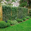A lush green garden with a tall ivy hedge providing privacy, a well-maintained lawn, and some decorative bushes in the foreground. Podgląd zdjęcia produktu