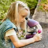 A young girl is looking through a microscope outdoors. Produktbild-Vorschau