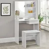 A white vanity table with a mirror and shelves, a white stool, and a framed picture on the wall. Produktbild-Vorschau