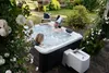 A couple relaxing in a hot tub in a garden setting. Produktbild-Vorschau