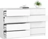 A white dresser with eight drawers is shown against a white background. A small green plant in a white pot sits on top of the dresser, along with a stack of books and a white paper crane. Produktbild-Vorschau